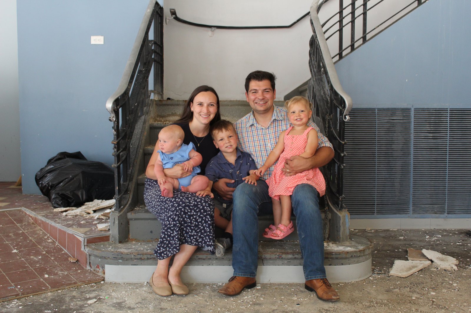Andrew Sharples with his wife and three children, seated on the original staircase inside the future taproom during early renovation
