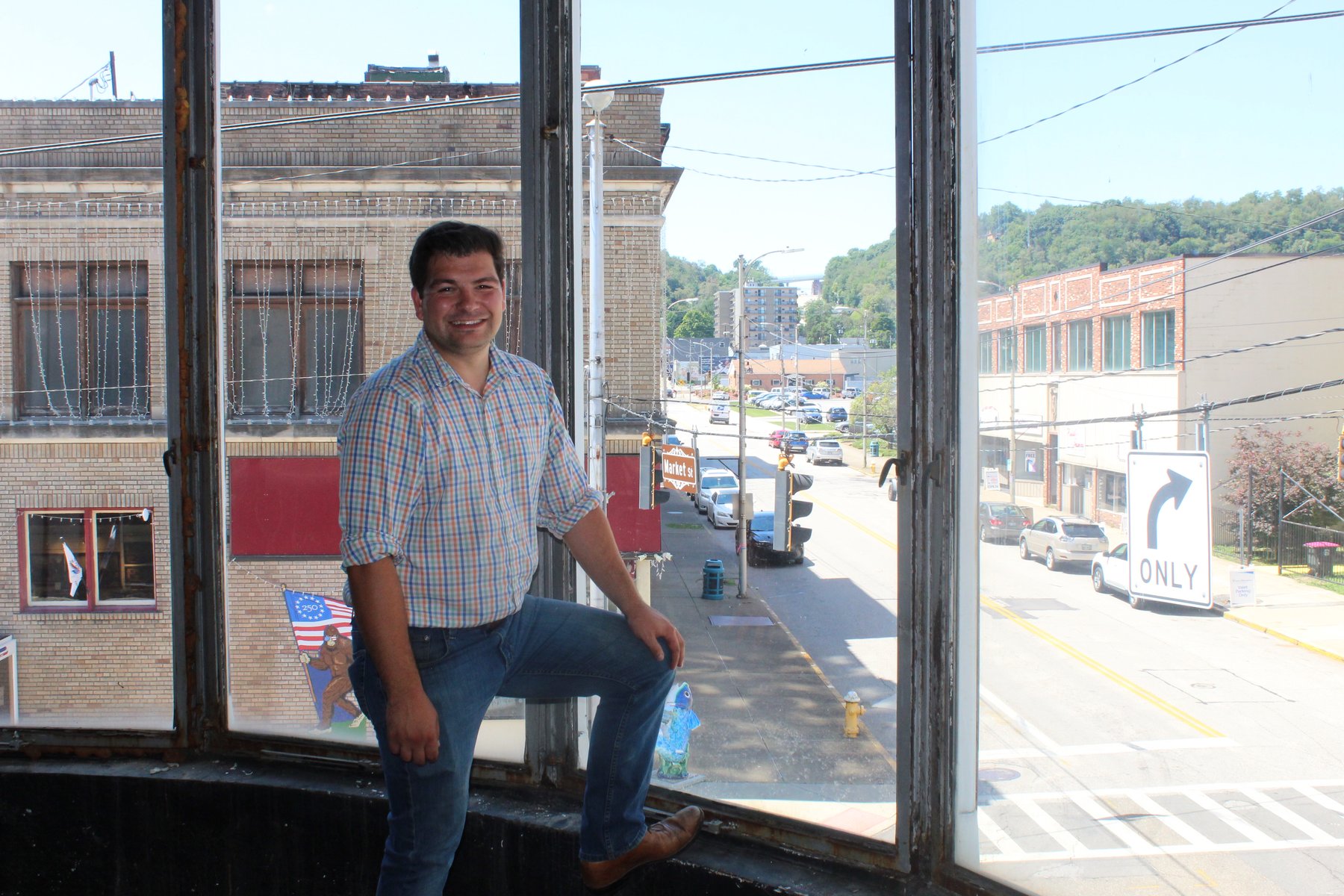 Oyo Brewing Co. founder Andrew Sharples in the building's curved corner window, overlooking the 4th and Market Street intersection in downtown Steubenville